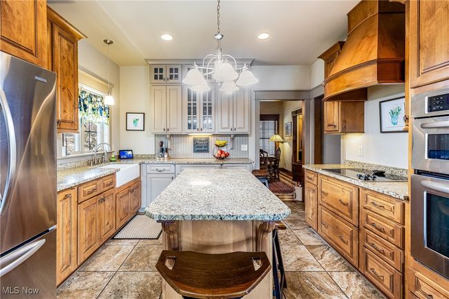 Kitchen with stainless steel appliances, premium range hood, a sink, glass insert cabinets, and pendant lighting | Image 20