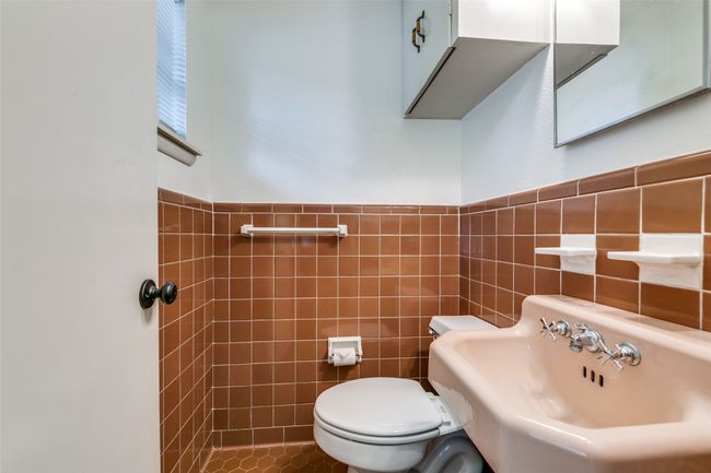 Primary bedroom's ensuite half bathroom with tile walls and wainscoting | Image 15