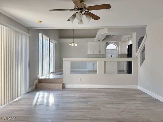 Kitchen with white cabinets, ceiling fan with notable chandelier, baseboards, and light wood-style flooring | Image 20