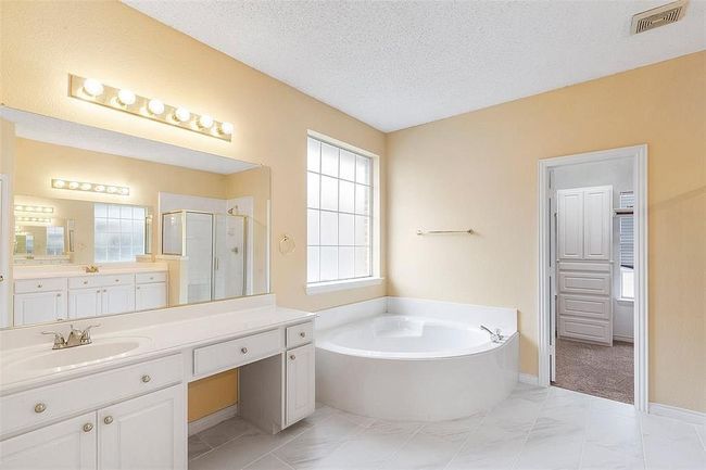 Full bath featuring marble finish floor, visible vents, a bath, a textured ceiling, and a stall shower | Image 16