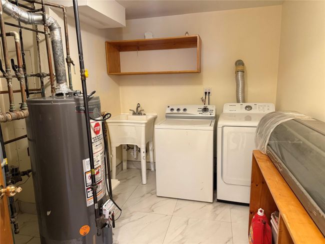 Washroom with washer and clothes dryer, a sink, marble finish floor, gas water heater, and laundry area | Image 20