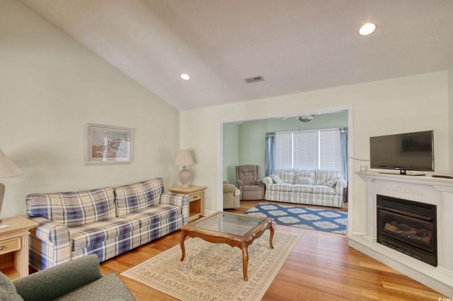 Living area with vaulted ceiling, wood finished floors, recessed lighting, and a glass covered fireplace | Image 11