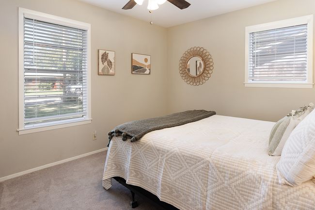 Carpeted bedroom featuring a ceiling fan, baseboards, and multiple windows | Image 28
