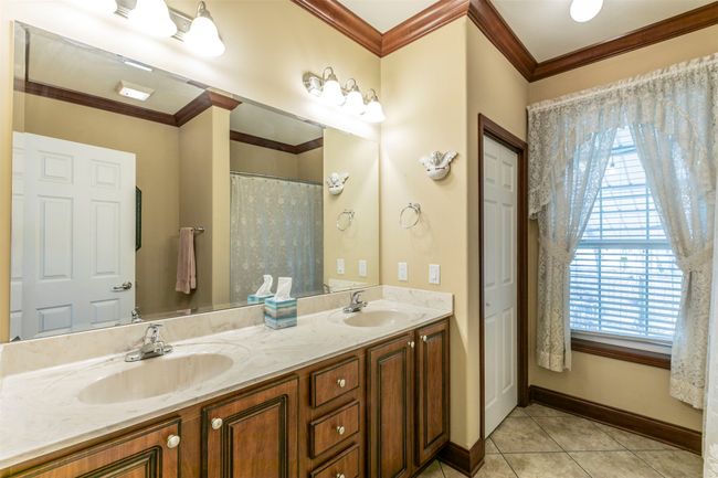 Bathroom with double vanity, a sink, baseboards, and tile patterned floors | Image 19