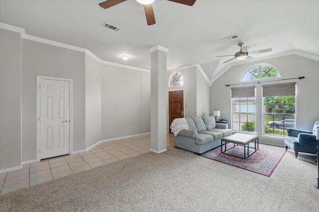 Tiled living room with a ceiling fan, baseboards, visible vents, and carpet | Image 9