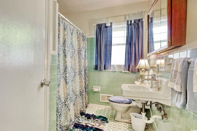 Bathroom featuring toilet, curtained shower, tile walls, tile patterned flooring, and wainscoting | Image 20