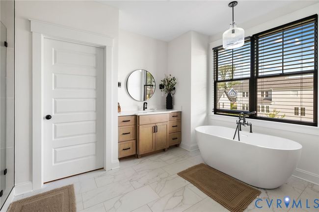 Full bath featuring marble finish floors, vanity, a freestanding tub, and healthy amount of natural light | Image 35