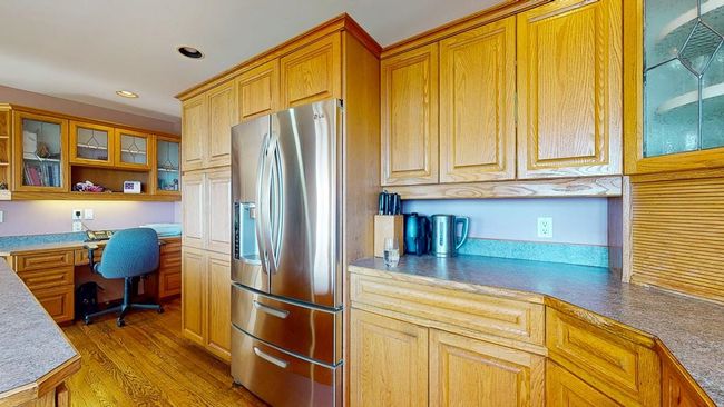 Kitchen with recessed lighting, glass insert cabinets, built in study area, and stainless steel fridge with ice dispenser | Image 14