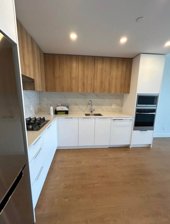 Kitchen featuring a sink, modern cabinets, backsplash, light countertops, and appliances with stainless steel finishes | Image 7