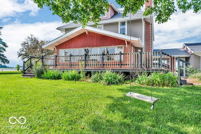 view of front of property featuring a wooden deck, a front yard, brick siding, and a shingled roof | Image 6
