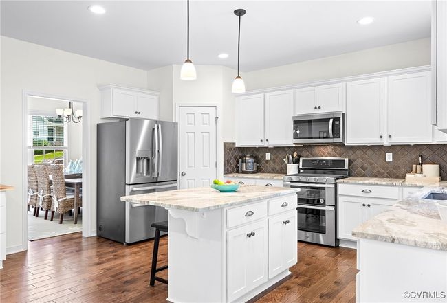 Stainless steel appliances, center island, granite counters, white cabinetry, gas cooking, corner pantry, tile backsplash & recessed lighting | Image 9