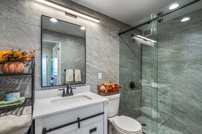 Bathroom with tile walls, vanity, and a stall shower | Image 7