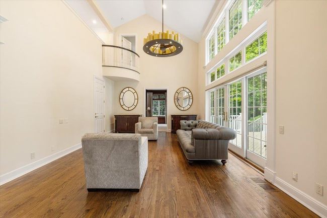 Living area featuring dark wood-type flooring, high vaulted ceiling, baseboards, and a chandelier | Image 11