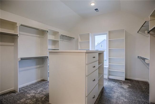 Walk in closet featuring dark colored carpet and lofted ceiling | Image 36