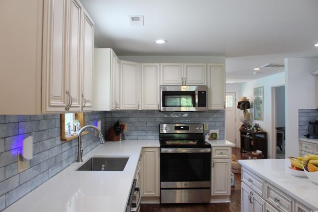 Kitchen featuring appliances with stainless steel finishes, decorative backsplash, recessed lighting, and dark wood-style floors | Image 5