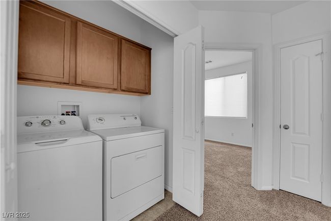 Laundry room featuring cabinet space, light colored carpet, and washer and clothes dryer | Image 16