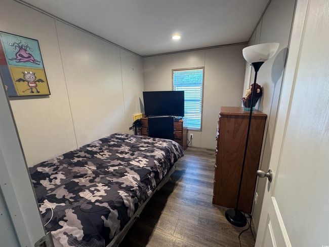 Bedroom with wood finished floors and a decorative wall | Image 14