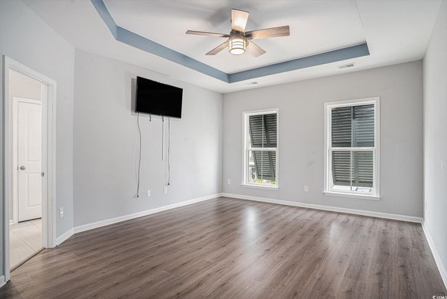 Empty room featuring a raised ceiling, a ceiling fan, and wood finished floors | Image 15