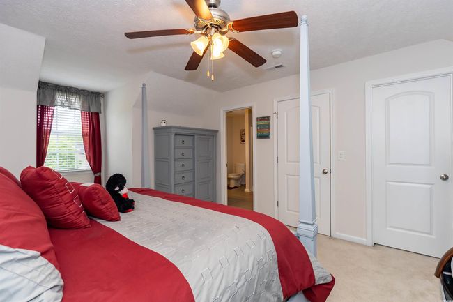 Bedroom with ensuite bathroom, ceiling fan, light carpet, baseboards, and visible vents | Image 18