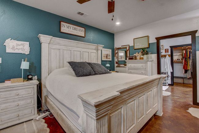 Bedroom featuring concrete flooring, a textured wall, visible vents, and a ceiling fan | Image 15