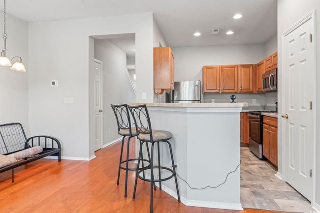 Kitchen featuring stainless steel appliances, a breakfast bar, brown cabinetry, recessed lighting, and light countertops | Image 8