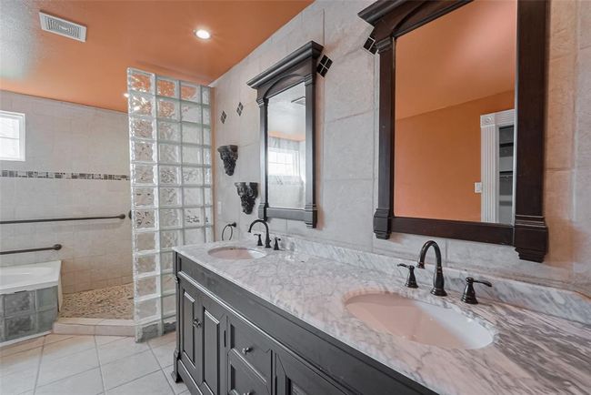 Stylish and dramatic, this bathroom offers dual vanities with marble countertops, matching framed mirrors, and contemporary lighting—making it a standout secondary suite. | Image 34