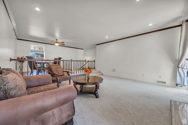 Living area featuring ornamental molding, carpet flooring, a ceiling fan, and visible vents | Image 10