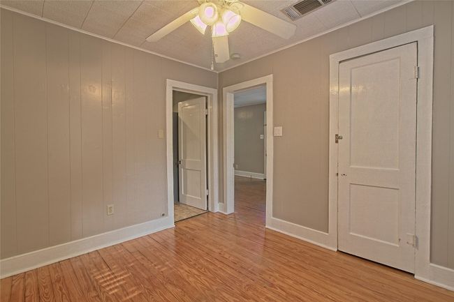 Empty room with light wood finished floors, a ceiling fan, and crown molding | Image 20