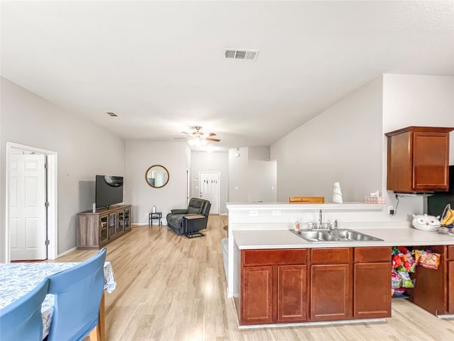 Kitchen featuring a sink, open floor plan, light wood-type flooring, light countertops, and ceiling fan | Image 10