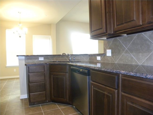 Kitchen featuring dishwasher, a peninsula, tasteful backsplash, and dark brown cabinets | Image 17