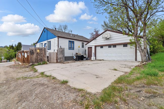 View of property exterior featuring an outbuilding, a detached garage, fence, and a shingled roof | Image 33