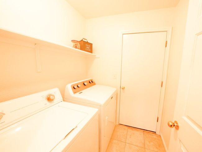 Clothes washing area with light tile patterned flooring, washing machine and dryer, and laundry area | Image 21