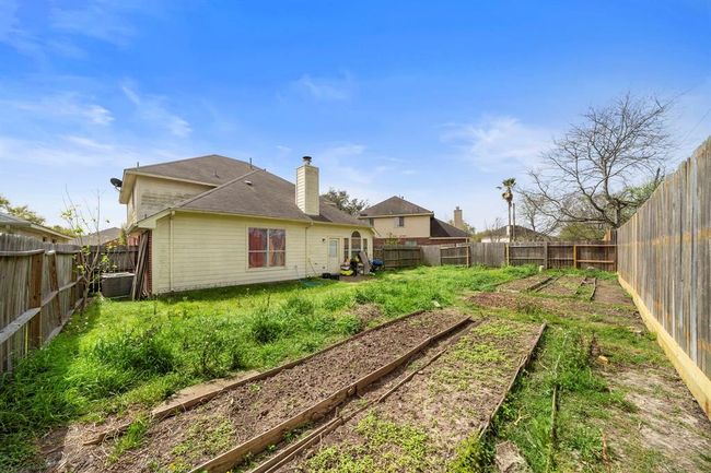 Whether you're hosting a barbecue or simply enjoying quiet evenings outside, this backyard provides the versatility and space. Garden beds along the fence line offer a great head start for any green thumb. | Image 32