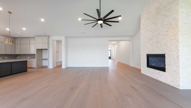 Unfurnished living room with ceiling fan, recessed lighting, light wood finished floors, high vaulted ceiling, and a stone fireplace | Image 10