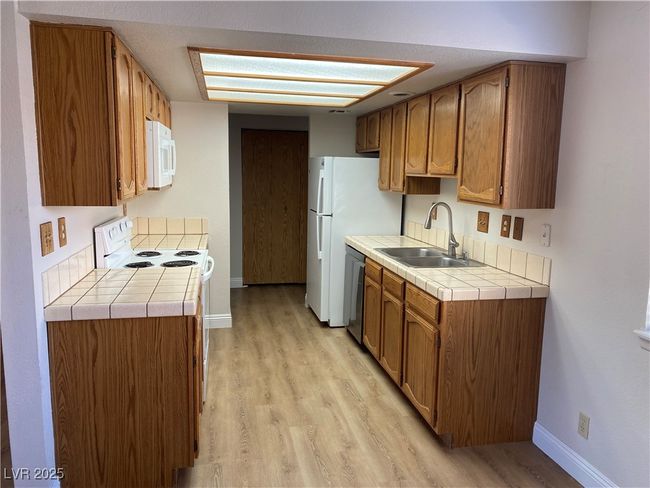Kitchen featuring a sink, white microwave, baseboards, and dishwasher | Image 5
