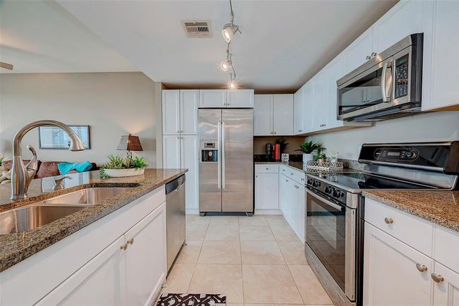 Modern kitchen with sleek granite countertops, stainless-steel appliances, and easy-care tile flooring. | Image 6