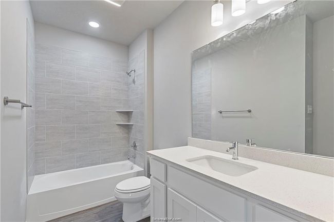 Full bathroom featuring toilet, tiled shower / bath, vanity, and hardwood / wood-style floors | Image 15