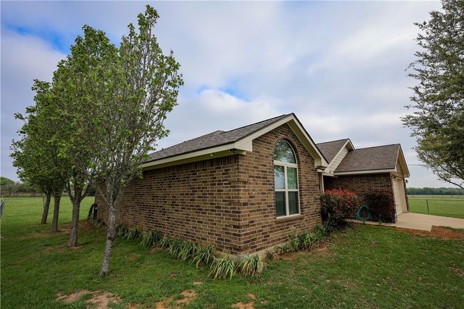 View of side of home with a lawn, brick siding, and roof with shingles | Image 11