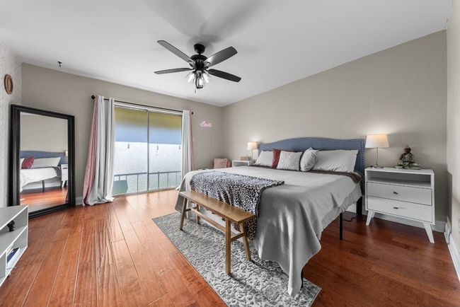 Primary bedroom featuring ceiling fan, wood-style flooring, a spacious walk-in closet and access to the balcony with a view to the pool | Image 25