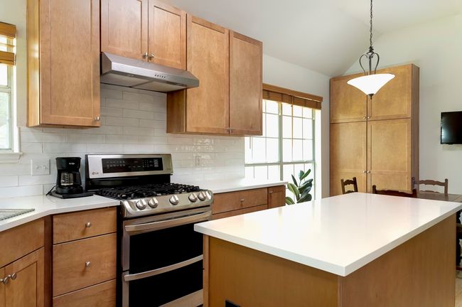 Kitchen featuring range with two ovens, under cabinet range hood, tasteful backsplash, plenty of natural light, and vaulted ceiling | Image 10