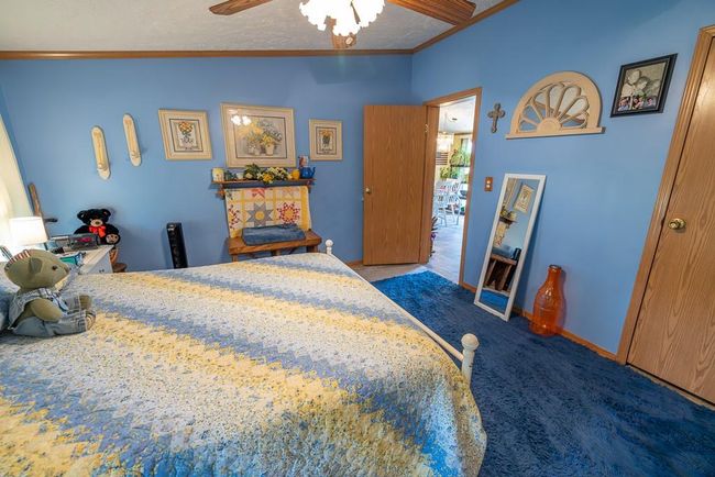Carpeted bedroom with a ceiling fan, lofted ceiling, and crown molding | Image 13