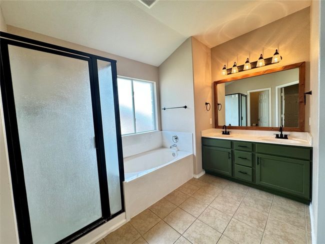 Bathroom featuring a garden tub, vaulted ceiling, double vanity, tile patterned floors, and a shower stall | Image 5