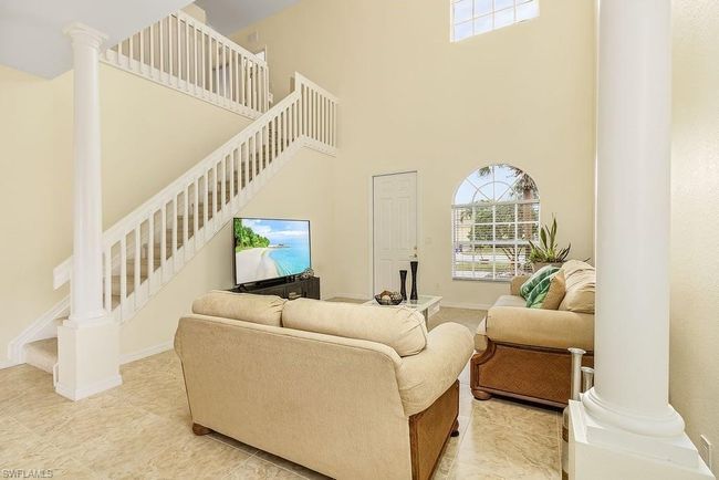 Living area with baseboards, decorative columns, a high ceiling, and stairway | Image 29
