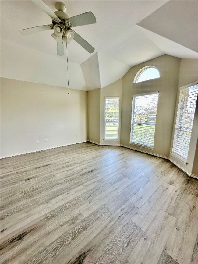Empty room featuring healthy amount of natural light, vaulted ceiling, wood finished floors, and ceiling fan | Image 13