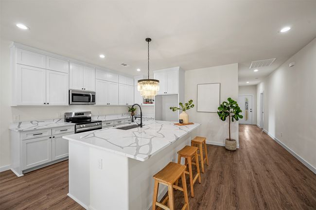 Kitchen featuring white cabinets, a sink, visible vents, stainless steel appliances, and dark wood-type flooring | Image 6