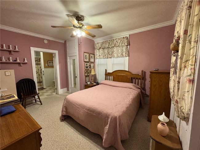 Bedroom with crown molding, light colored carpet, ensuite bath, and a ceiling fan | Image 19