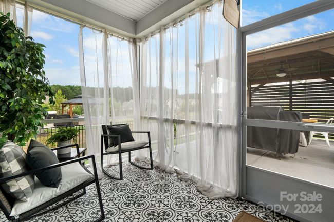 Screened porch features custom tiled flooring, shear curtains and access to the fenced backyard. | Image 38