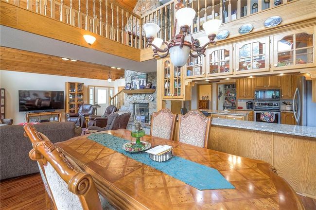 Dining room featuring a fireplace, a chandelier, wood finished floors, and a high ceiling | Image 11