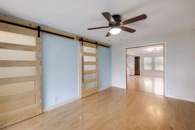 Unfurnished bedroom featuring a barn door, wood finished floors, baseboards, and ceiling fan | Image 30