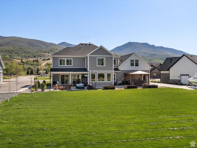 Back of property with board and batten siding, a patio area, a mountain view, and a lawn | Image 54